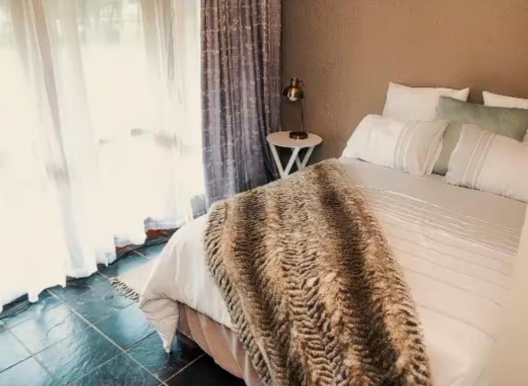 Single room with warm lighting and soft sage throw at Bafenyi Care Centre